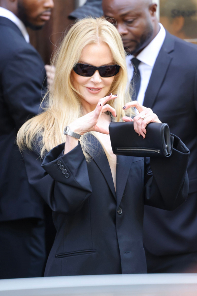 Nicole Kidman makes a heart shape with her hands wearing a black suit and sunglasses