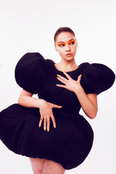 Madelyn Cline wearing orange eye makeup and a black sculptural dress